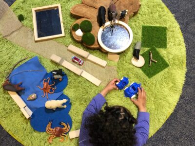 A child playing with lots of little toys and materials
